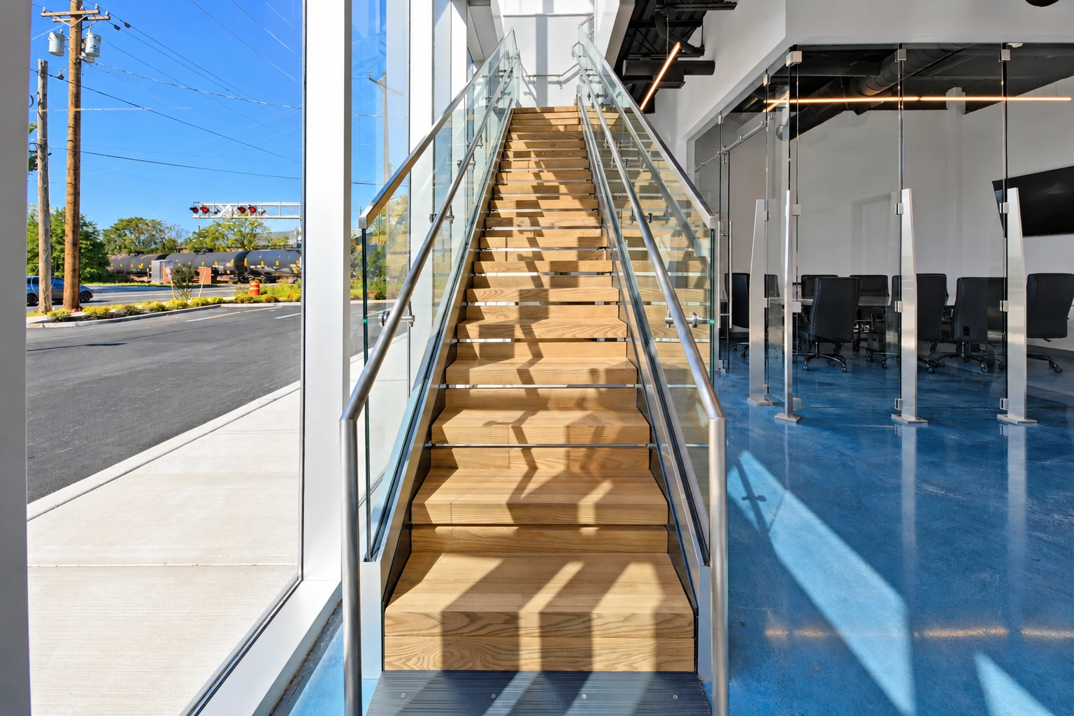 Sunlit staircase with glass railings and a blue floor